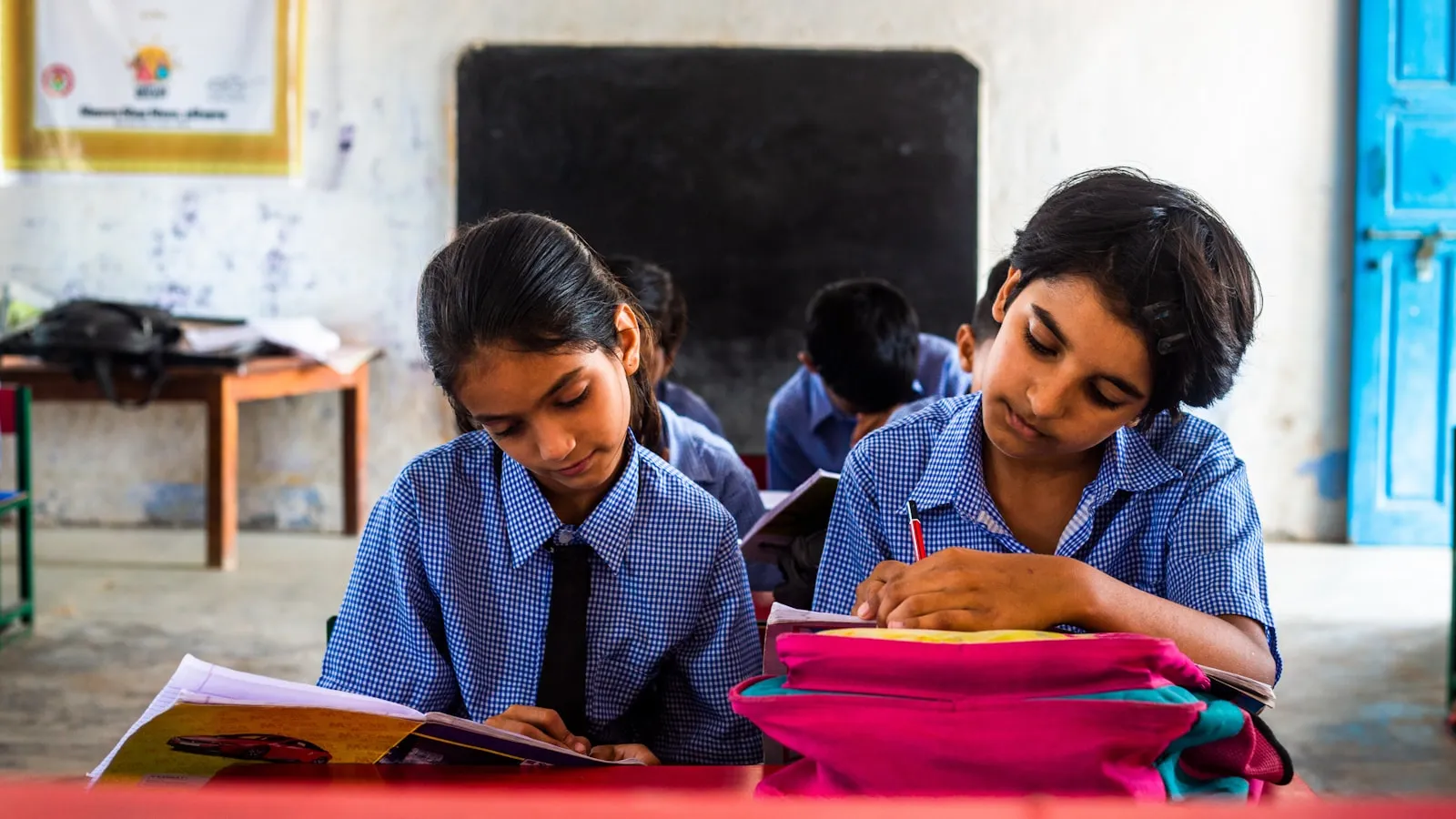 Two students writing together at a classroom desk